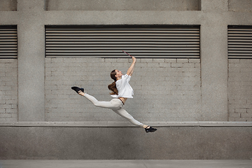 Image showing Jumping young woman in front of buildings, on the run in jump high