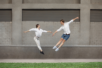 Image showing Jumping young couple in front of buildings, on the run in jump high