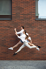 Image showing Jumping young couple in front of buildings, on the run in jump high