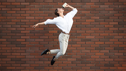 Image showing Jumping young woman in front of buildings, on the run in jump high