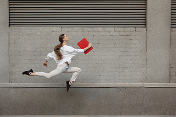 Image showing Jumping young woman in front of buildings, on the run in jump high