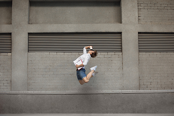 Image showing Jumping young man in front of buildings, on the run in jump high