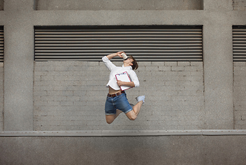 Image showing Jumping young man in front of buildings, on the run in jump high