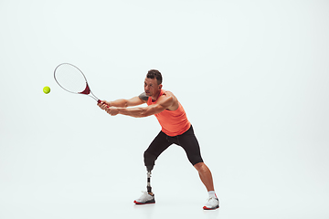 Image showing Athlete with disabilities or amputee isolated on white studio background. Professional male tennis player with leg prosthesis training and practicing in studio.