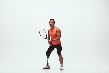 Image showing Athlete with disabilities or amputee isolated on white studio background. Professional male tennis player with leg prosthesis training and practicing in studio.