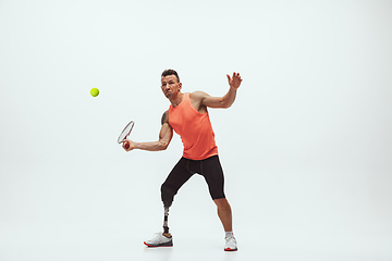 Image showing Athlete with disabilities or amputee isolated on white studio background. Professional male tennis player with leg prosthesis training and practicing in studio.