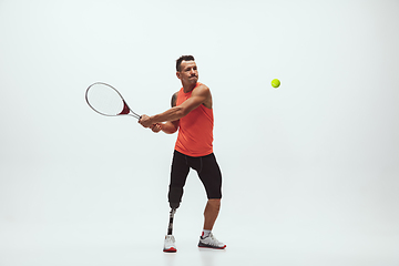 Image showing Athlete with disabilities or amputee isolated on white studio background. Professional male tennis player with leg prosthesis training and practicing in studio.