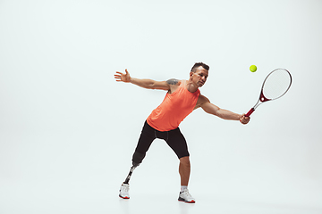 Image showing Athlete with disabilities or amputee isolated on white studio background. Professional male tennis player with leg prosthesis training and practicing in studio.