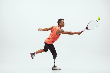 Image showing Athlete with disabilities or amputee isolated on white studio background. Professional male tennis player with leg prosthesis training and practicing in studio.