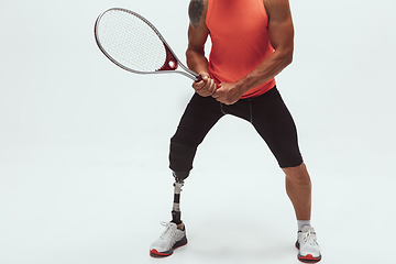 Image showing Athlete with disabilities or amputee isolated on white studio background. Professional male tennis player with leg prosthesis training and practicing in studio.