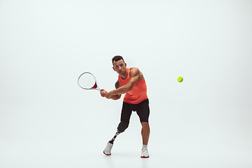 Image showing Athlete with disabilities or amputee isolated on white studio background. Professional male tennis player with leg prosthesis training and practicing in studio.