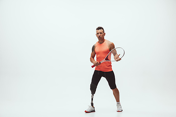 Image showing Athlete with disabilities or amputee isolated on white studio background. Professional male tennis player with leg prosthesis training and practicing in studio.