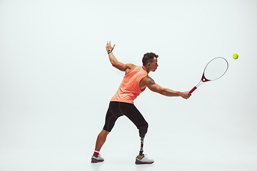 Image showing Athlete with disabilities or amputee isolated on white studio background. Professional male tennis player with leg prosthesis training and practicing in studio.