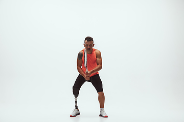 Image showing Athlete with disabilities or amputee isolated on white studio background. Professional male tennis player with leg prosthesis training and practicing in studio.