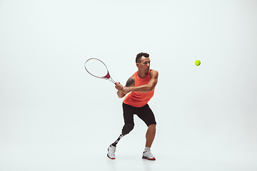 Image showing Athlete with disabilities or amputee isolated on white studio background. Professional male tennis player with leg prosthesis training and practicing in studio.