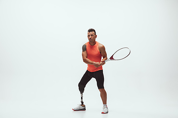 Image showing Athlete with disabilities or amputee isolated on white studio background. Professional male tennis player with leg prosthesis training and practicing in studio.