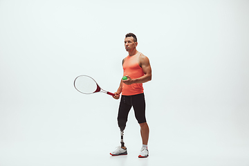 Image showing Athlete with disabilities or amputee isolated on white studio background. Professional male tennis player with leg prosthesis training and practicing in studio.