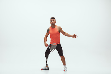 Image showing Athlete with disabilities or amputee isolated on white studio background. Professional male tennis player with leg prosthesis training and practicing in studio.