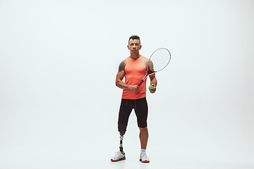 Image showing Athlete with disabilities or amputee isolated on white studio background. Professional male tennis player with leg prosthesis training and practicing in studio.