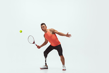 Image showing Athlete with disabilities or amputee isolated on white studio background. Professional male tennis player with leg prosthesis training and practicing in studio.