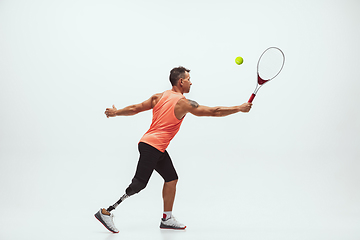 Image showing Athlete with disabilities or amputee isolated on white studio background. Professional male tennis player with leg prosthesis training and practicing in studio.