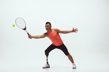 Image showing Athlete with disabilities or amputee isolated on white studio background. Professional male tennis player with leg prosthesis training and practicing in studio.