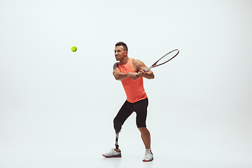 Image showing Athlete with disabilities or amputee isolated on white studio background. Professional male tennis player with leg prosthesis training and practicing in studio.