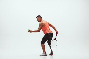 Image showing Athlete with disabilities or amputee isolated on white studio background. Professional male tennis player with leg prosthesis training and practicing in studio.