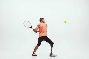 Image showing Athlete with disabilities or amputee isolated on white studio background. Professional male tennis player with leg prosthesis training and practicing in studio.