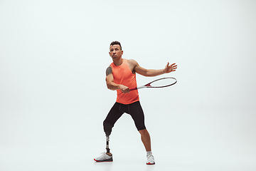 Image showing Athlete with disabilities or amputee isolated on white studio background. Professional male tennis player with leg prosthesis training and practicing in studio.