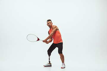 Image showing Athlete with disabilities or amputee isolated on white studio background. Professional male tennis player with leg prosthesis training and practicing in studio.
