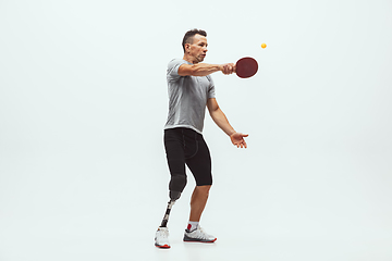 Image showing Athlete with disabilities or amputee isolated on white studio background. Professional male table tennis player with leg prosthesis training and practicing in studio.