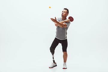 Image showing Athlete with disabilities or amputee isolated on white studio background. Professional male table tennis player with leg prosthesis training and practicing in studio.