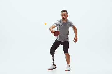 Image showing Athlete with disabilities or amputee isolated on white studio background. Professional male table tennis player with leg prosthesis training and practicing in studio.