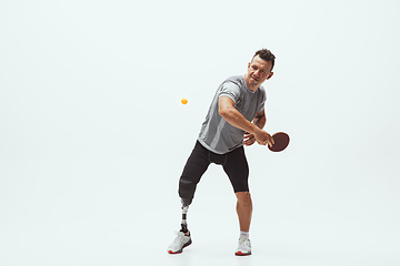 Image showing Athlete with disabilities or amputee isolated on white studio background. Professional male table tennis player with leg prosthesis training and practicing in studio.