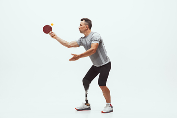 Image showing Athlete with disabilities or amputee isolated on white studio background. Professional male table tennis player with leg prosthesis training and practicing in studio.