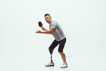 Image showing Athlete with disabilities or amputee isolated on white studio background. Professional male table tennis player with leg prosthesis training and practicing in studio.