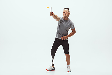 Image showing Athlete with disabilities or amputee isolated on white studio background. Professional male table tennis player with leg prosthesis training and practicing in studio.