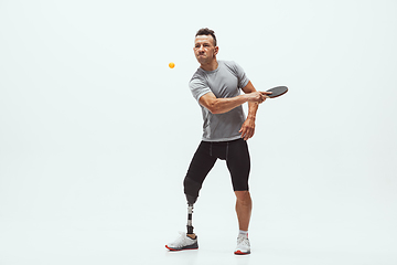 Image showing Athlete with disabilities or amputee isolated on white studio background. Professional male table tennis player with leg prosthesis training and practicing in studio.