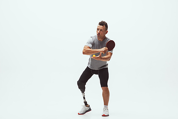 Image showing Athlete with disabilities or amputee isolated on white studio background. Professional male table tennis player with leg prosthesis training and practicing in studio.