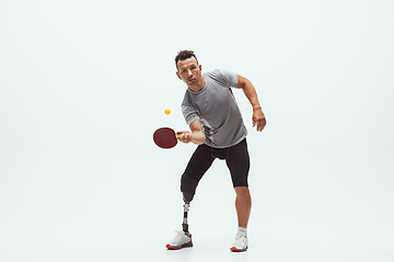 Image showing Athlete with disabilities or amputee isolated on white studio background. Professional male table tennis player with leg prosthesis training and practicing in studio.