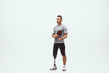 Image showing Athlete with disabilities or amputee isolated on white studio background. Professional male table tennis player with leg prosthesis training and practicing in studio.