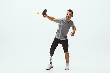 Image showing Athlete with disabilities or amputee isolated on white studio background. Professional male table tennis player with leg prosthesis training and practicing in studio.