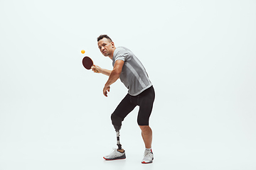 Image showing Athlete with disabilities or amputee isolated on white studio background. Professional male table tennis player with leg prosthesis training and practicing in studio.