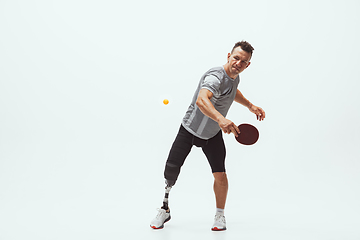 Image showing Athlete with disabilities or amputee isolated on white studio background. Professional male table tennis player with leg prosthesis training and practicing in studio.