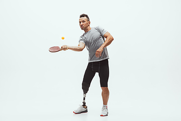 Image showing Athlete with disabilities or amputee isolated on white studio background. Professional male table tennis player with leg prosthesis training and practicing in studio.