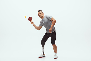 Image showing Athlete with disabilities or amputee isolated on white studio background. Professional male table tennis player with leg prosthesis training and practicing in studio.