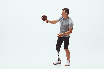 Image showing Athlete with disabilities or amputee isolated on white studio background. Professional male table tennis player with leg prosthesis training and practicing in studio.