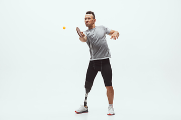 Image showing Athlete with disabilities or amputee isolated on white studio background. Professional male table tennis player with leg prosthesis training and practicing in studio.