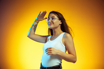 Image showing Portrait of young caucasian woman isolated on gradient yellow studio background